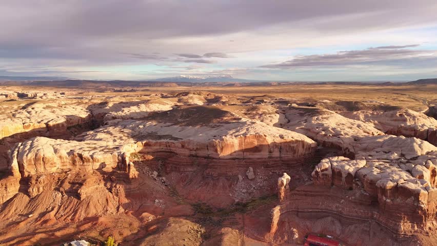 Aerial view of red rock formations with buildings nestled below, contrasting textures of the desert landscape, Bluff, Utah, United States.