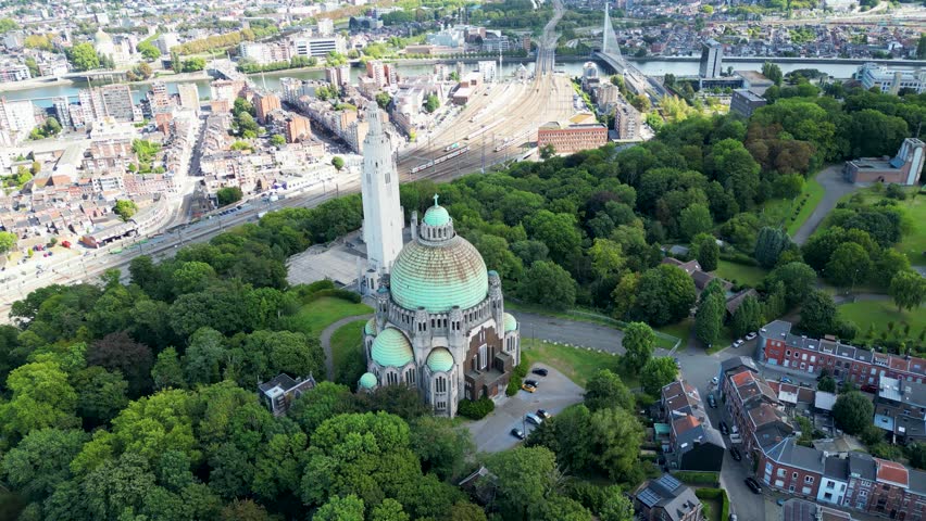 Aerial view of the Cointe Intercommunal Memorial surrounded by vibrant green trees, contrasting with the city
