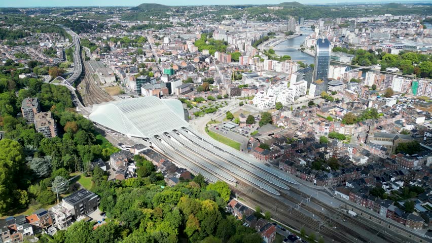Aerial view of the modern Liège-Guillemins railway station, surrounded by a dense cityscape with the Meuse river winding through it, Liège, Wallonia, Belgium.