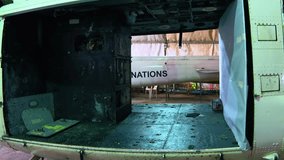 Empty cargo bay of a united nations military helicopter. The worn and weathered interior is visible, looking out towards an aircraft hangar - Powered by Shutterstock - Get 15% off with code: PIKWIZARD15