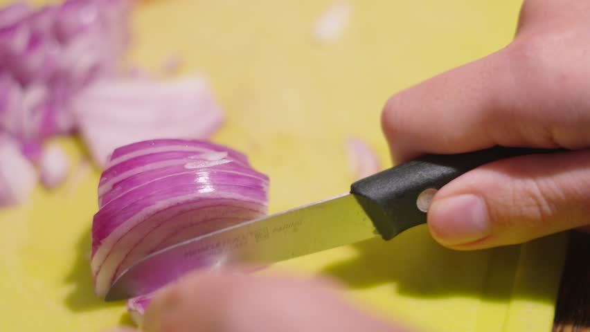 Red Onion Being Sliced on Chopping Board with Small Knife with Pieces in Background. Healthy Organic Food Prep Clip.