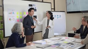 A group of people are in a meeting room with a whiteboard and a projector. The man in the center is giving a presentation - Powered by Shutterstock - Get 15% off with code: PIKWIZARD15