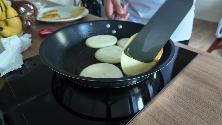 A close-up of a chef preparing a pancake in a restaurant setting with a electric stove