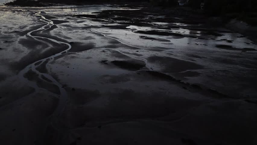 A pull-back drone footage of the mudflats on the coast of St. Andrews town, in Charlotte County, New Brunswick, Canada at sunset