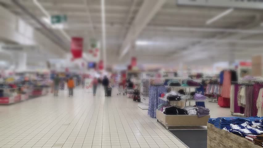 Shoppers browsing through clothing sections in a spacious retail store.