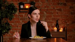 A woman eats pasta with fried chicken. An elegant female enjoys a romantic dinner in a cozy restaurant with brick walls, candles, and soft lighting. - Powered by Shutterstock - Get 15% off with code: PIKWIZARD15