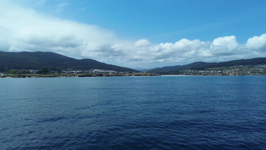 Calm sea and hills under blue sky at Lugo beach, evokes tranquility
