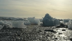 Waves crashing onto icebergs at Diamond Beach, Iceland. Glacial ice blocks sparkle on the black sand shore, creating a dramatic seascape with ocean waves under soft evening light. - Powered by Shutterstock - Get 15% off with code: PIKWIZARD15
