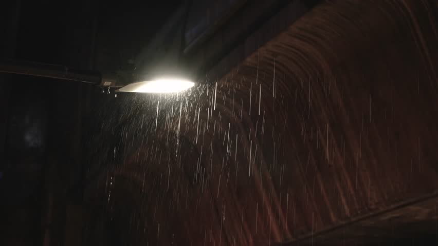Street lamp in heavy rain under concrete metro station structure at night cinematic view
