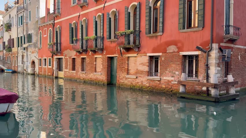 Water canal in Venice, Italy. Red building reflected on surface