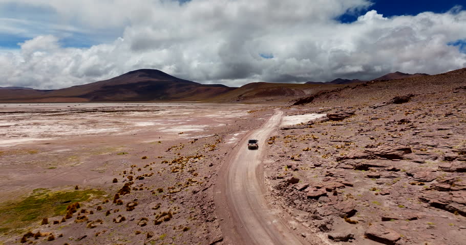 Vehicle driving on road trip in Siloli Desert, Bolivia. Aerial tracking