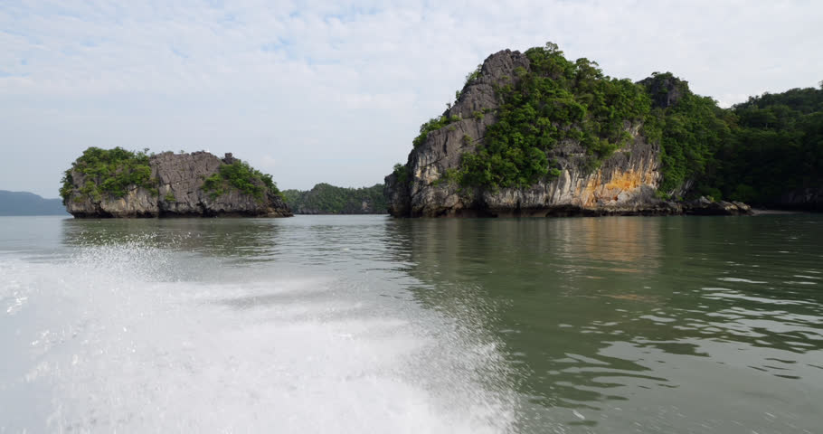 Scenic karst limestone islets line the northern shoreline of Kilim Geoforest Park, their rough rocky sides shaped by erosion and topped with lush tropical greenery. Scenic shoreline of Langkawi island