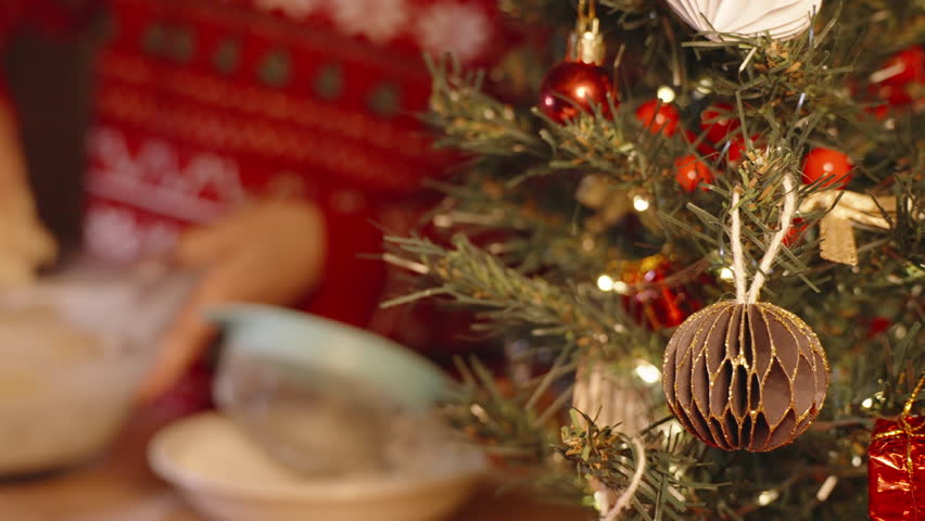 Woman in Red Sweater Kneading Thick Dough in Bowl Beside Sifter and Flour Bowl under Christmas Tree Lights.