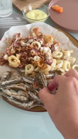 Anonymous eat fried fish with homemade mayonnaise. Deep fried anchovies and seafood on plate in kitchen. Healthy eating and organic products.