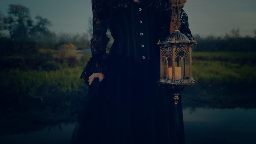 Fairy tale silhouette gothic woman queen hand hold lantern lamp warm light walking across bridge over river fog dusk night nature dark blue sky. long black lace dress. Fantasy scared girl cropped face