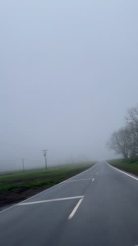 Misty Foggy Road vertical FPV footage. POV car driving through a Misty and desolate Rural Field. Concept of sad, personal development, motivational phrase, inspirational quote.