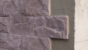 Wall prepared for decorative stone cladding with the first tiles already installed. Close-up view of the facade before full masonry work and exterior renovation. - Powered by Shutterstock - Get 15% off with code: PIKWIZARD15