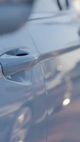 Close-up of a person's hand bringing the phone closer to the car handle and the app opens the door. Concept of a modern smart car. The white car is easily unlocked using a mobile app.