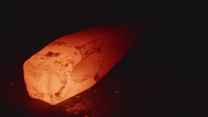 Blacksmiths hammers a rough iron on anvil.
