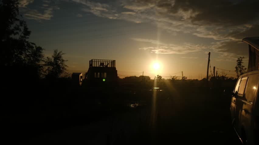 Camper van parked at a scenic campsite during golden hour, presenting a tranquil outdoor lifestyle, travel, and vacation experience with a camp table on the grass