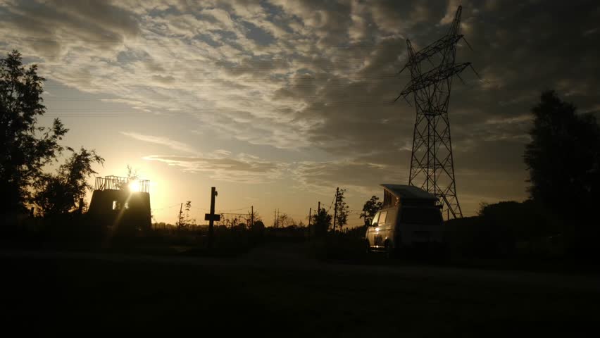 Camper van parked at a scenic campsite during golden hour, presenting a tranquil outdoor lifestyle, travel, and vacation experience with a camp table on the grass