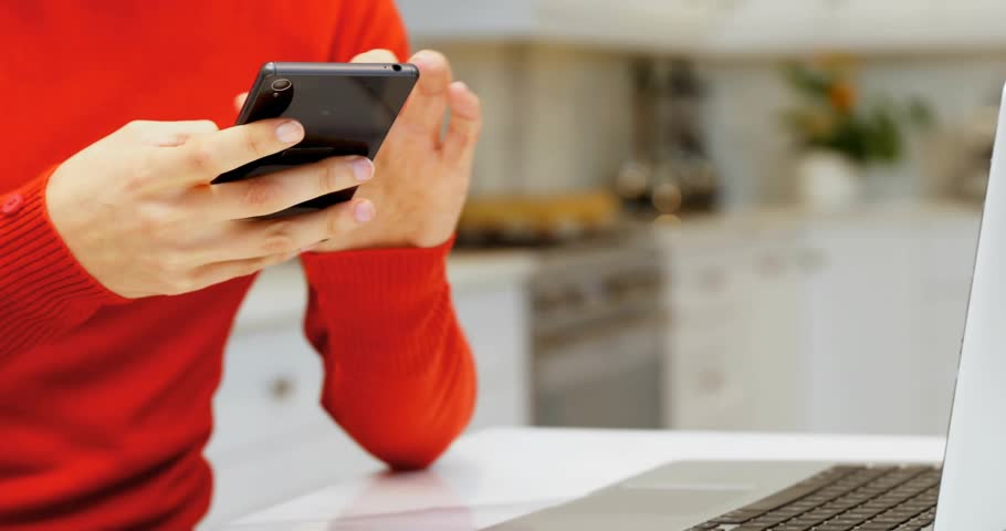 Woman tapping smartphone, activating floating emoticon spheres around laptop for technology demo. Technology, innovation, digital, communication, expression, modern, creativity