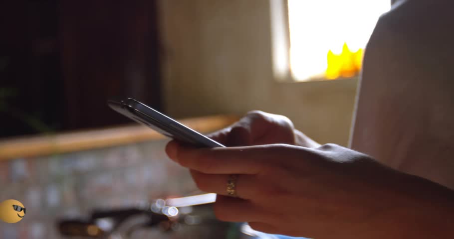 Woman holding smartphone tapping screen, causing emoji cloud multiplying and dispersing for ads. Interactive, digital, animated, communication, social, vibrant, playful