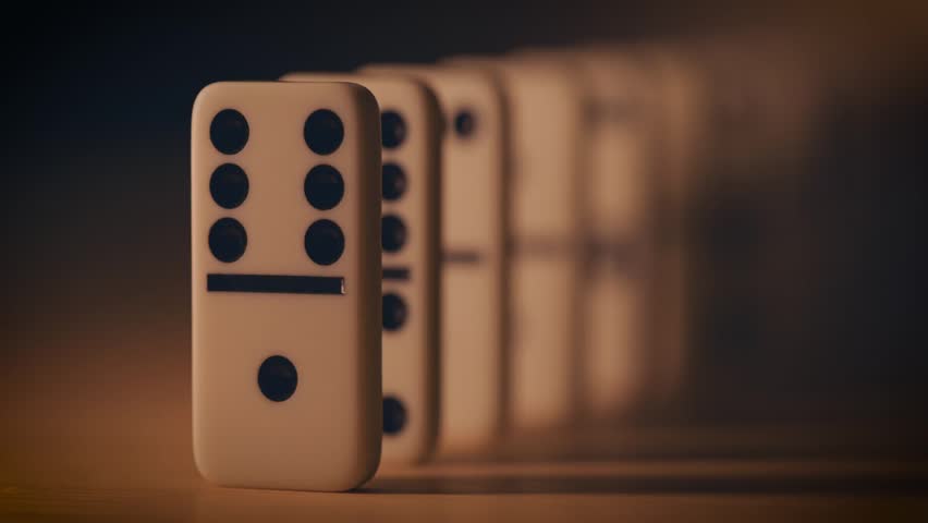 Close-up of dominoes falling in sequence, capturing motion, chain reaction, and kinetic action in a playful or creative setup.