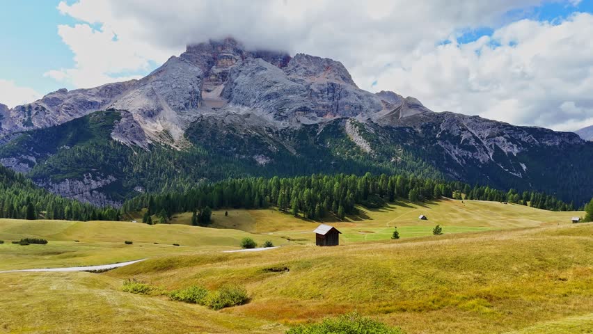 Beautiful landscape in Dolomites, Italy.  Malga Prato Piazza meadow and big mountain summit and ridge. South Tyrol region in Italy. Trekking and bike road in Italy Dolomites. Wooden cabin hut.