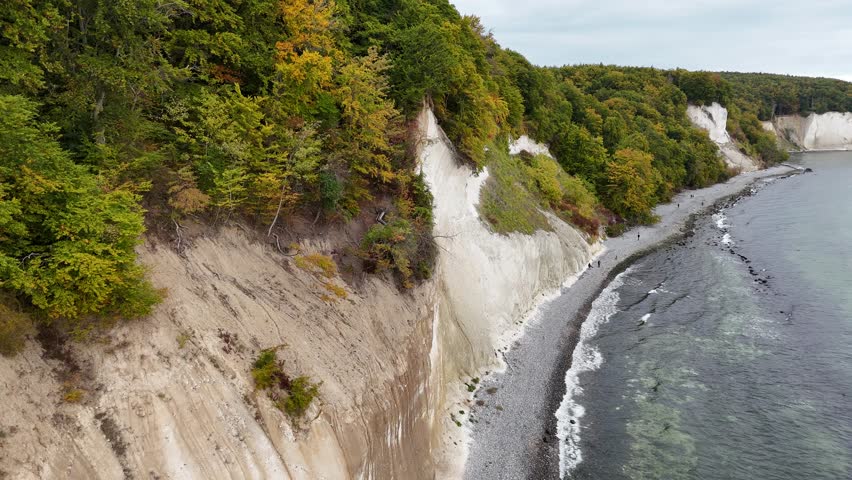 Areal drone footage of the  chalk cliffs at Jasmund National Park of Rügen Island, Germany. The video shows colorful forest landscapes, white limestone cliffs and the blue water of the Baltic Sea