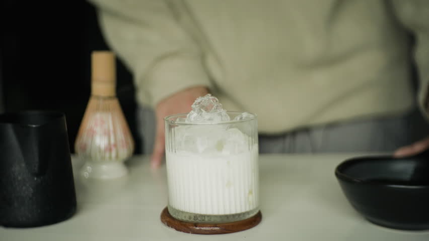  people pouring low-fat fresh milk into iced green tea in cups, homemade green tea drinks at home. 