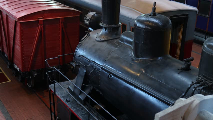 A black train engine sits next to a bright red train car on the tracks.