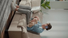 Vertical Video. A Mother Sits on the Couch With Her Baby, Struggling to Focus on Her Laptop As the Infant Cries. Scene Highlights Remote Work Stress, Parenting Challenges, and Emotional Balance. - Powered by Shutterstock - Get 15% off with code: PIKWIZARD15