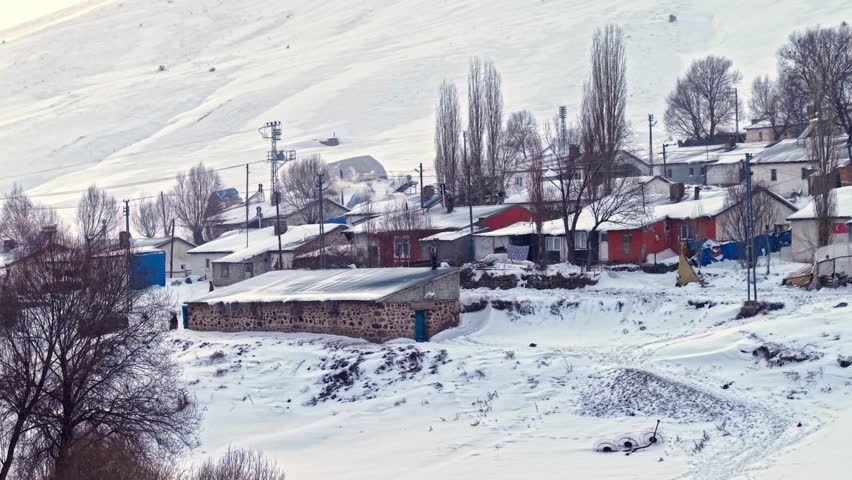 Aerial view of a snow-covered village with aligned houses, quiet roads, and bare trees. The calm beauty of rural winter life.