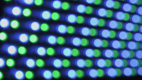 Abstract out-of-focus shot of a large LED panel, showing a grid of circular lights flashing and changing colors, creating a vibrant red, green, blue, and yellow bokeh effect on a dark background. - Powered by Shutterstock - Get 15% off with code: PIKWIZARD15