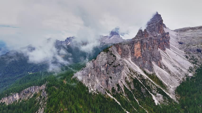 Beautiful landscapes of Dolomites mountains and the forests around the high ridges. Dolomites forest. Croda da Lago peak. Aerial view from the drone. Cloud scape.