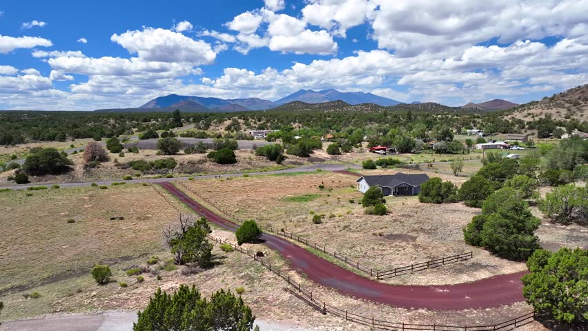 Aerial view of houses nestled among trees, with mountains in the distance under a partly cloudy sky, Flagstaff, Arizona, United States.