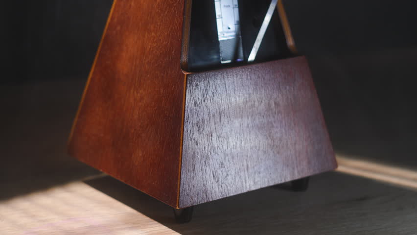 Close up working metronome on dark bTicking metronome symbolizing time, rhythm, and balance. Represents the passage of life, discipline, and the heartbeat of creativity. 