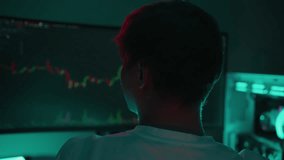 Rear view of young professional trading cryptocurrency studying digital chart on computer screen, dark room lit by vibrant neon lighting, concentrating on market analysis and investment strategy. - Powered by Shutterstock - Get 15% off with code: PIKWIZARD15