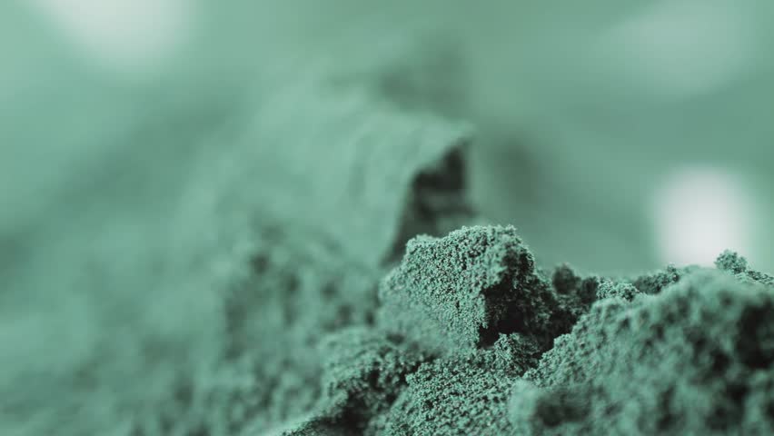 Green chlorella algae powder on a wooden spoon, top view. Healthy nutritional supplement.