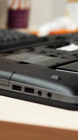 Engineer performs laptop maintenance within workshop. Device opened for diagnostic. Screwdriver used for precise repair and upgrade. Computer warranty covers fix. Support ensures continuous servicing