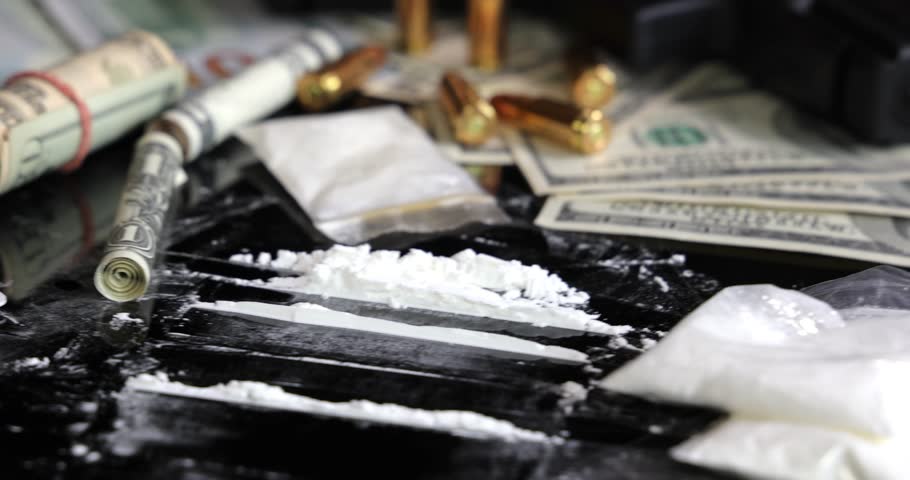 Illegal drugs and cash with gun and bullets on table - crime scene. Gun with bullets lying on the black table. Criminal problems. Drugs and money on black background. Illegal selling