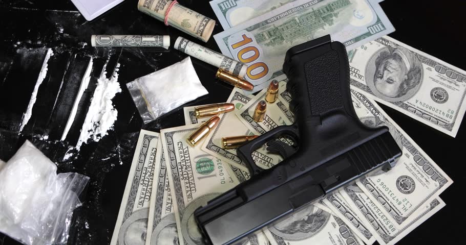 Illegal drugs and cash with gun and bullets on table - crime scene. Gun with bullets lying on the black table. Criminal problems. Drugs and money on black background. Illegal selling