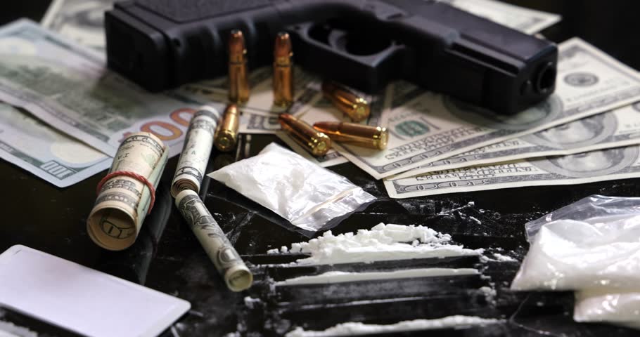 Illegal drugs and cash with gun and bullets on table - crime scene. Gun with bullets lying on the black table. Criminal problems. Drugs and money on black background. Illegal selling