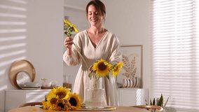 Woman putting beautiful sunflowers into vase at wooden table indoors - Powered by Shutterstock - Get 15% off with code: PIKWIZARD15