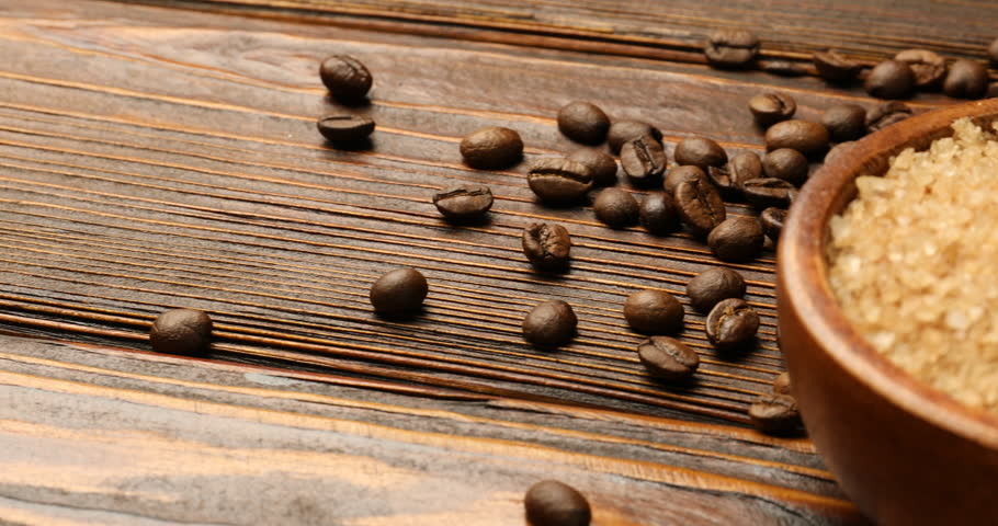 Different types of sea salt, coffee beans and dried orange slices on wooden table, closeup. Camera moving right