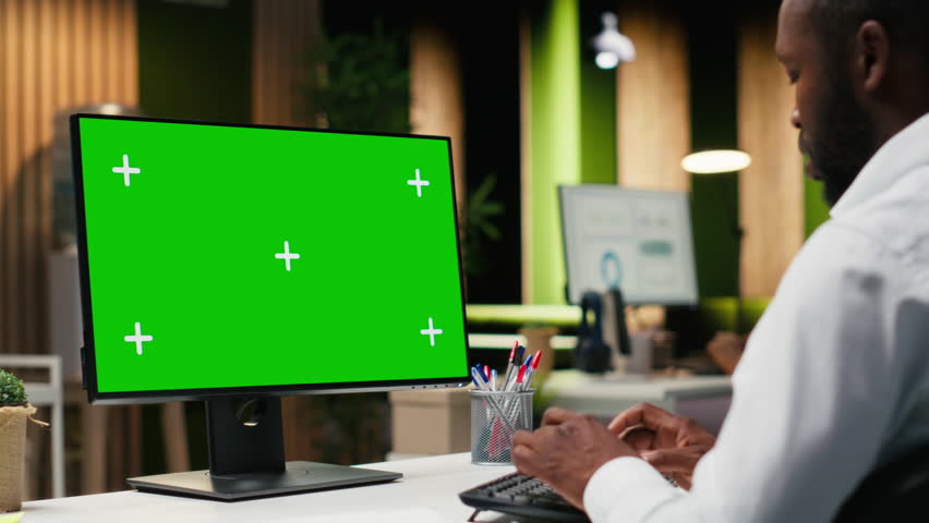 Mockup chroma key on desktop pc with black analyst analyzing KPI metrics, applying a strategic mindset to business development plans. Support innovation and goals achievement. Camera B.