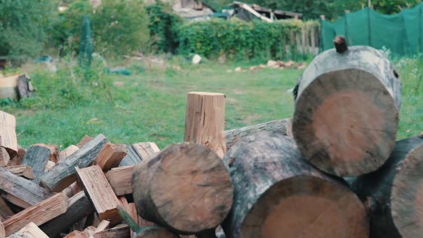 Pile of Chopped Firewood and Logs on Green Grass in Rural Yard | Winter Fuel Preparation at Countryside Home | Traditional Heating Supply Storage | Sustainable Living Concept