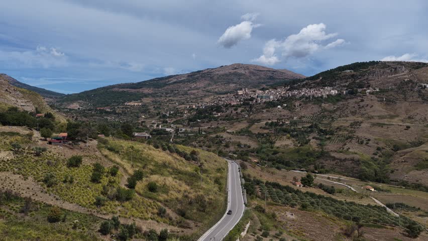 Aerial drone view of Petralia Sottana, a historic Sicilian mountain town surrounded by scenic hills and the Madonie Mountains, featuring traditional stone houses and panoramic landscapes, Sicily Italy
