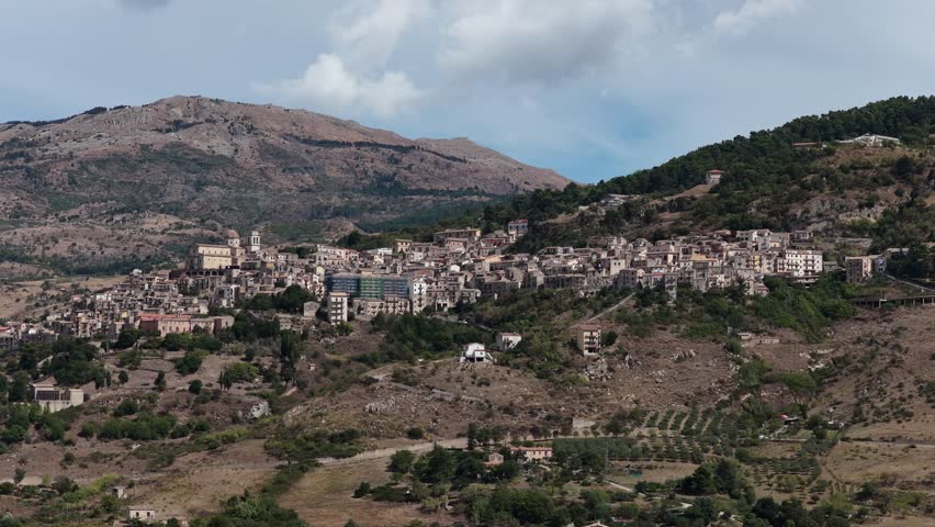 Aerial drone view of Petralia Sottana, a historic Sicilian mountain town surrounded by scenic hills and the Madonie Mountains, featuring traditional stone houses and panoramic landscapes, Sicily Italy